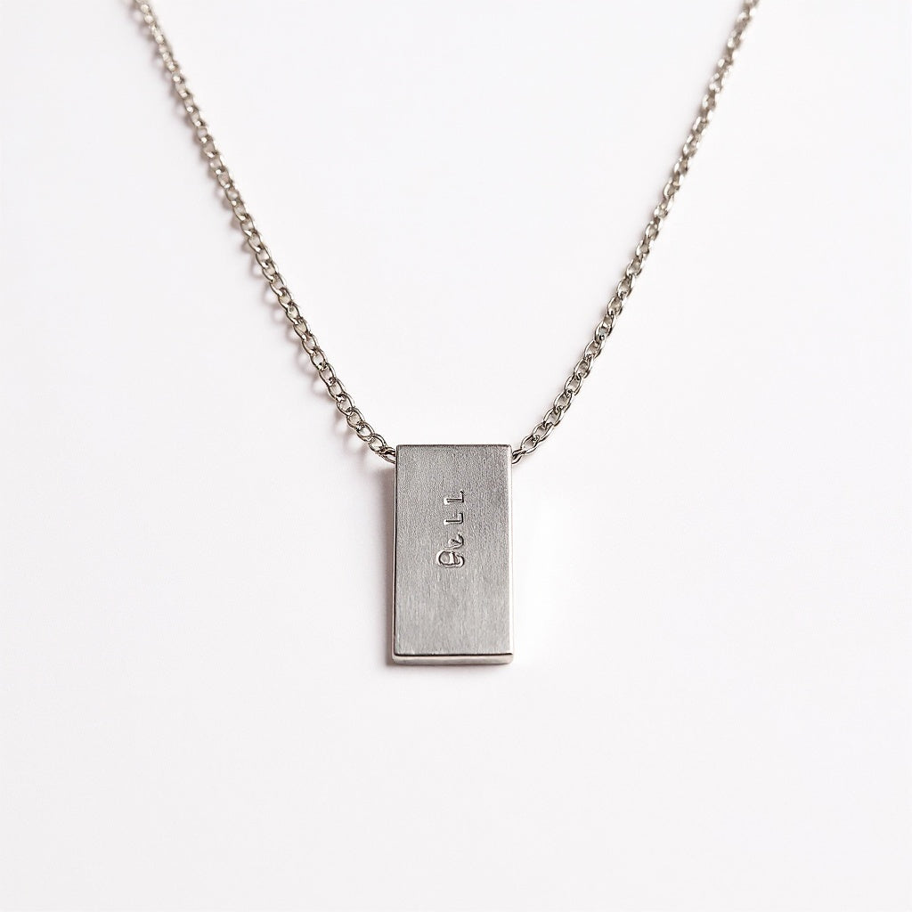 Close-up of engraved detail on sterling silver bar necklace, macro texture shot